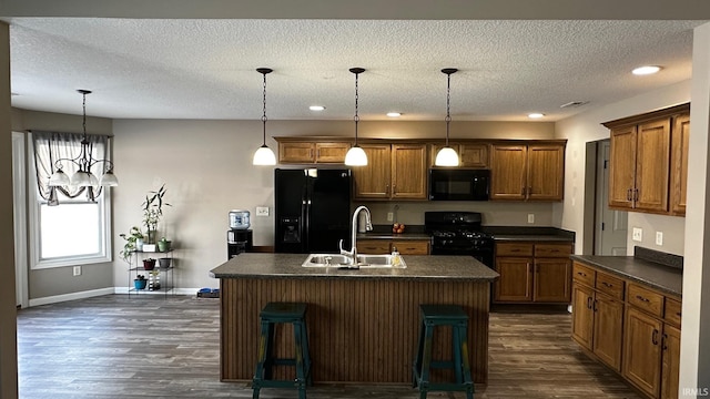 kitchen with pendant lighting, a center island with sink, black appliances, and sink