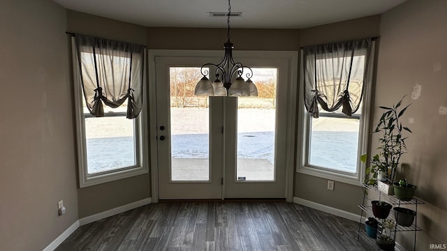 unfurnished dining area featuring dark hardwood / wood-style floors, a healthy amount of sunlight, and a chandelier