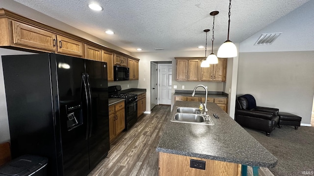 kitchen featuring pendant lighting, black appliances, sink, a textured ceiling, and an island with sink