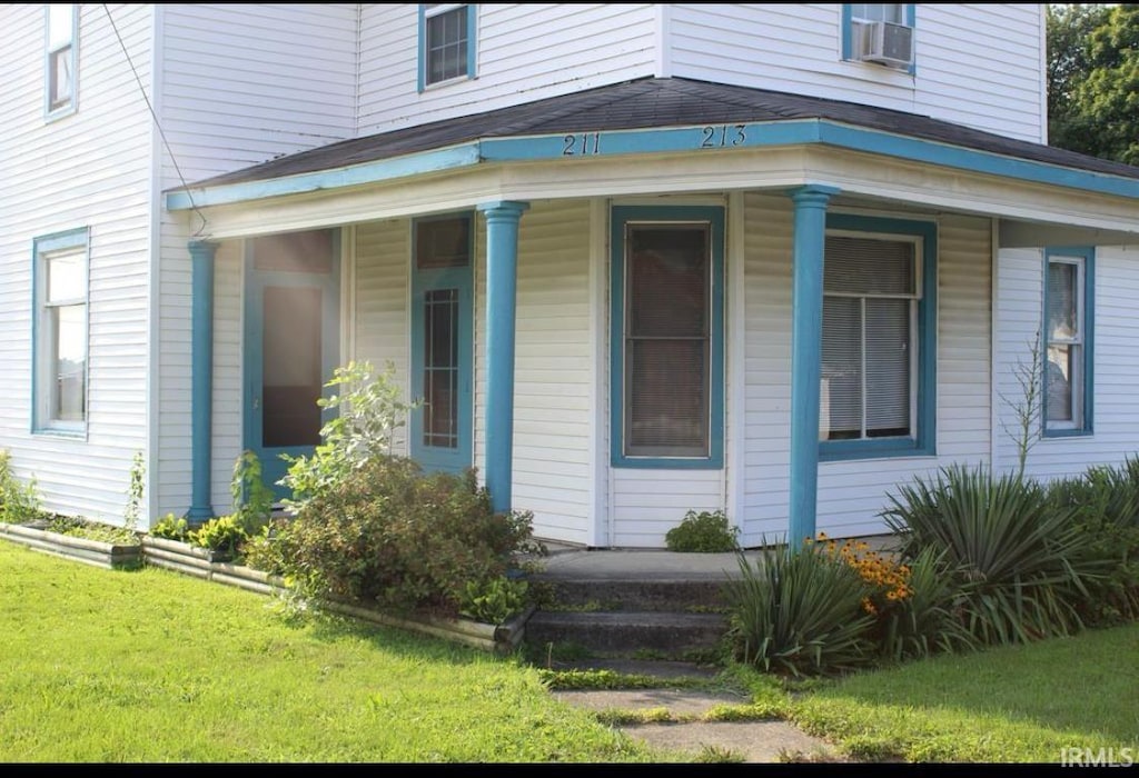 view of side of property featuring covered porch and a lawn