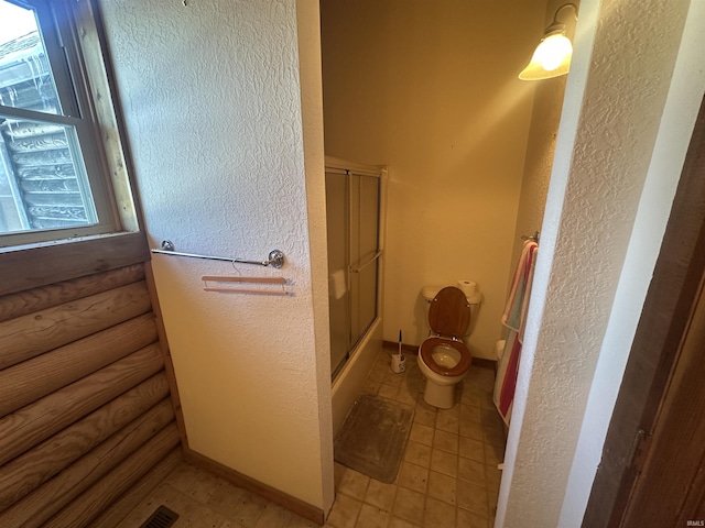 bathroom featuring tile patterned floors, a wealth of natural light, enclosed tub / shower combo, and toilet