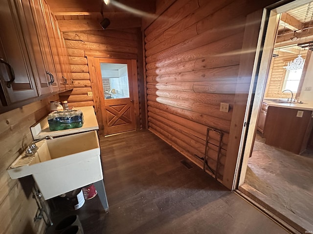 interior space with log walls, dark hardwood / wood-style floors, wooden ceiling, and sink