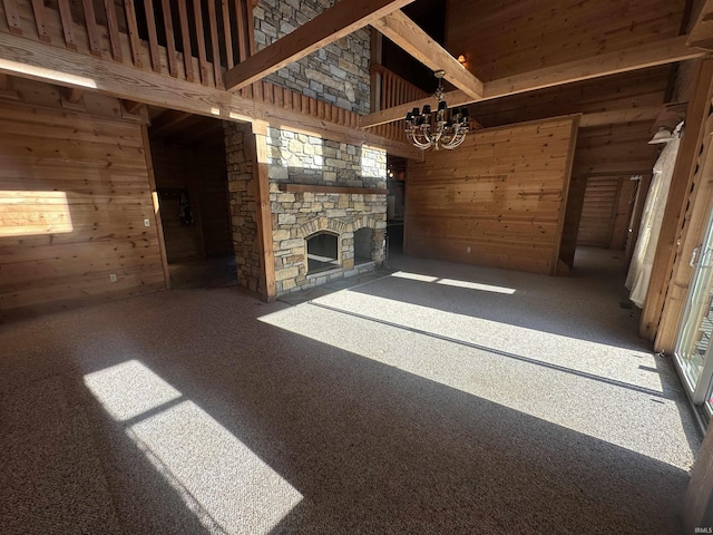 unfurnished living room featuring a chandelier, a high ceiling, a fireplace, and wooden walls