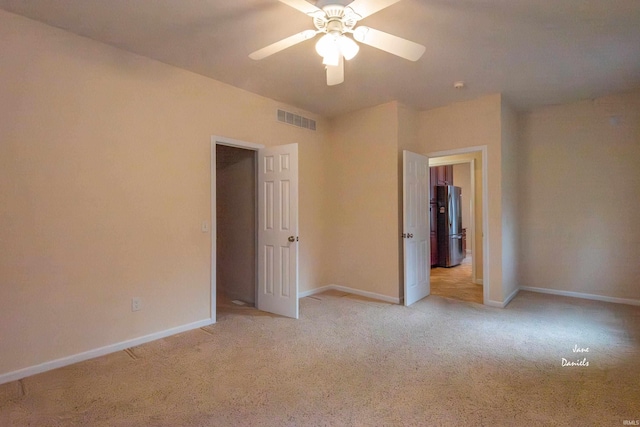 spare room with ceiling fan and light carpet