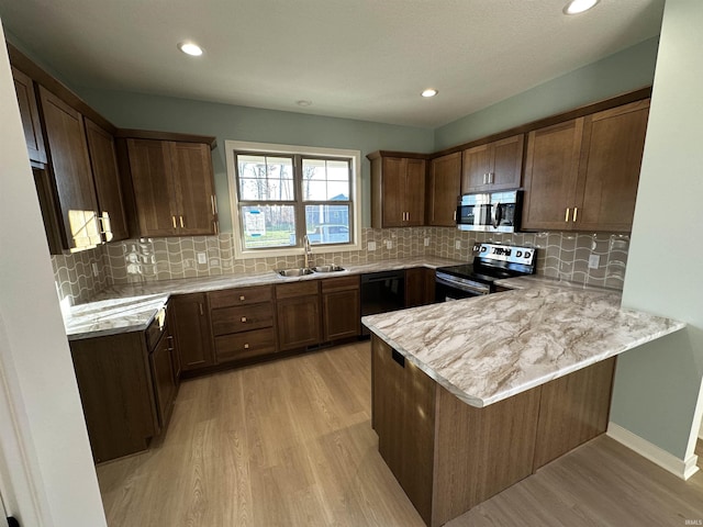 kitchen featuring kitchen peninsula, appliances with stainless steel finishes, light wood-type flooring, sink, and a breakfast bar area