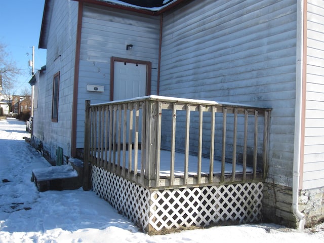 snow covered property entrance featuring a wooden deck