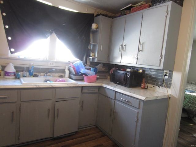 kitchen featuring backsplash, gray cabinets, sink, and dark wood-type flooring