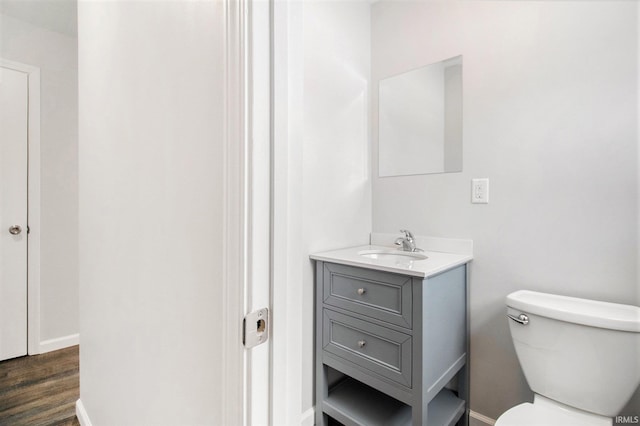 bathroom with hardwood / wood-style flooring, vanity, and toilet