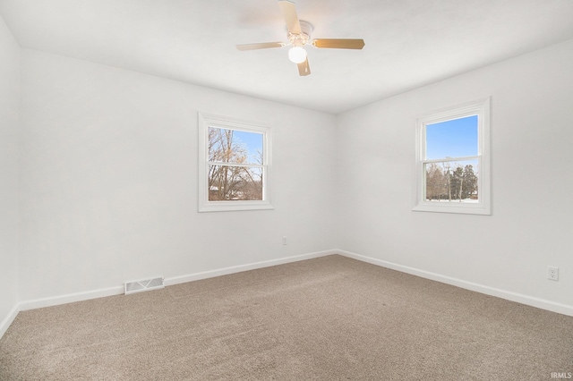 carpeted spare room with a wealth of natural light and ceiling fan