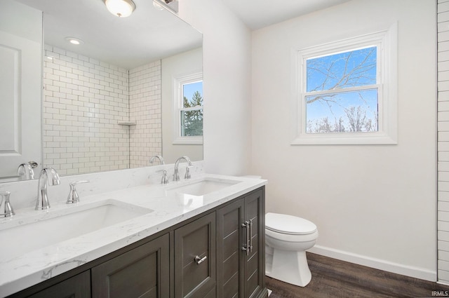 bathroom featuring tiled shower, hardwood / wood-style floors, vanity, and toilet