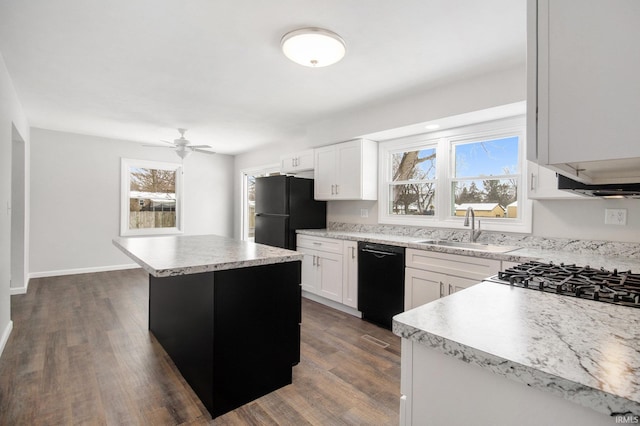 kitchen with ceiling fan, sink, a kitchen island, white cabinets, and black appliances