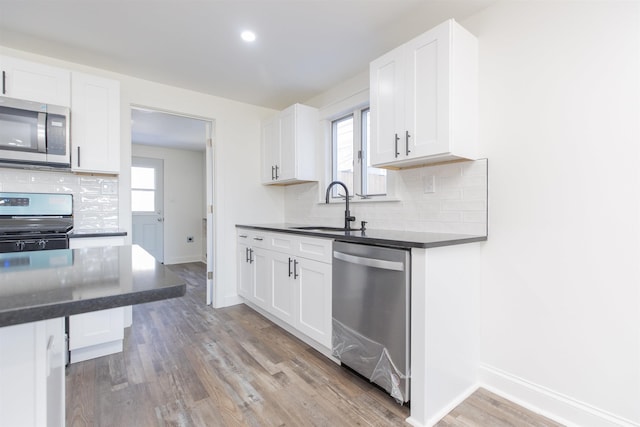 kitchen featuring appliances with stainless steel finishes, light wood-type flooring, white cabinetry, and sink