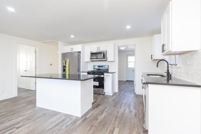 kitchen featuring backsplash, stainless steel appliances, sink, white cabinets, and a center island