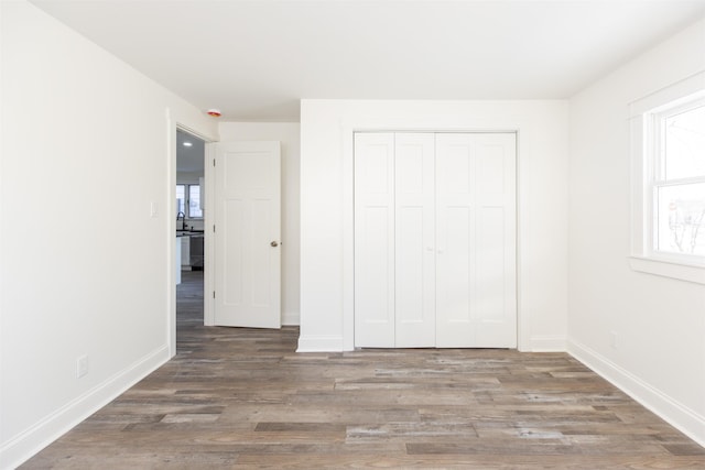 unfurnished bedroom with a closet and dark wood-type flooring