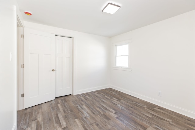 unfurnished bedroom featuring a closet and dark wood-type flooring