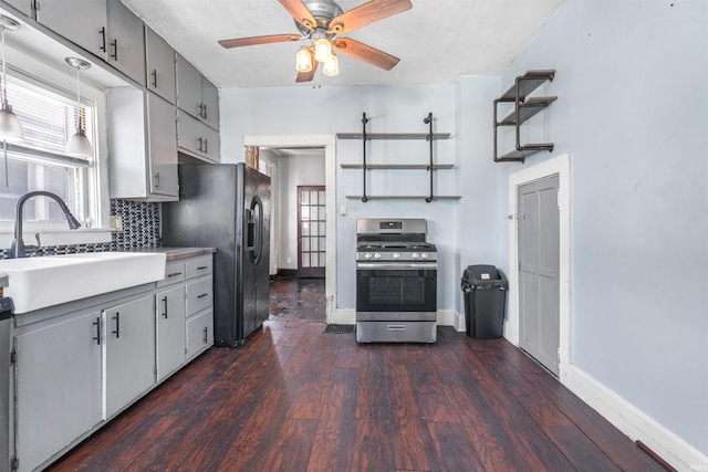 kitchen featuring black fridge, sink, stainless steel gas stove, dark hardwood / wood-style floors, and tasteful backsplash