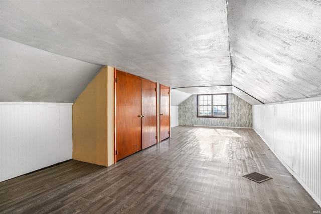 bonus room featuring hardwood / wood-style floors, lofted ceiling, and a textured ceiling