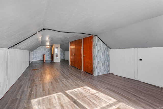 additional living space with wooden walls, lofted ceiling, and hardwood / wood-style flooring