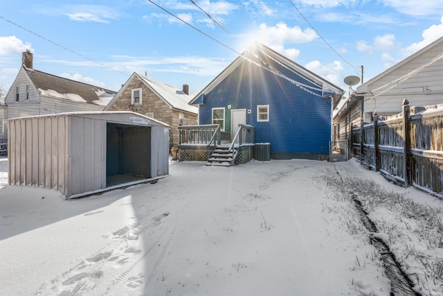 rear view of house with central air condition unit, a deck, and a storage shed