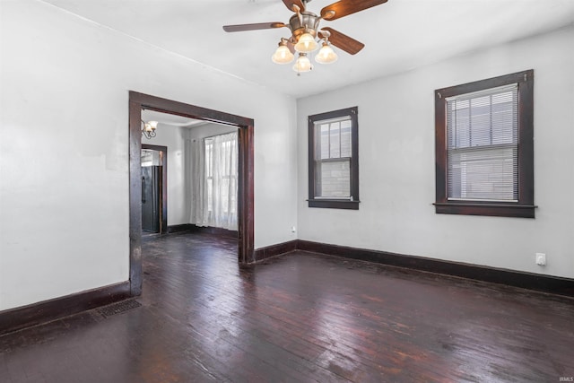 empty room featuring dark wood-type flooring and ceiling fan with notable chandelier