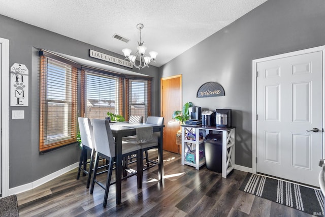 dining space featuring dark hardwood / wood-style flooring, lofted ceiling, a textured ceiling, and an inviting chandelier