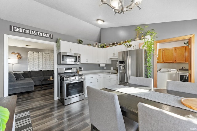 kitchen featuring separate washer and dryer, white cabinets, stainless steel appliances, and vaulted ceiling