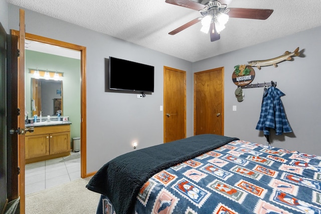 tiled bedroom with ceiling fan, sink, a textured ceiling, and connected bathroom