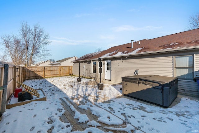 snow covered rear of property featuring a hot tub