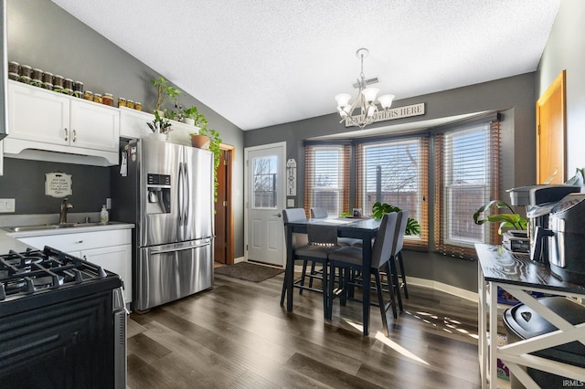 kitchen with white cabinets, stainless steel appliances, lofted ceiling, and a notable chandelier