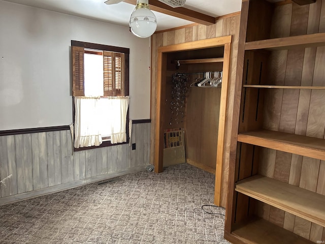 interior space with carpet floors, a closet, and wooden walls