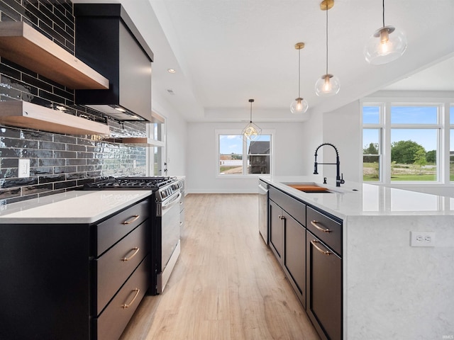 kitchen featuring decorative backsplash, stainless steel appliances, sink, a center island with sink, and hanging light fixtures