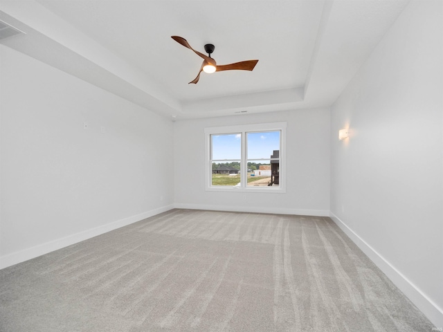 carpeted spare room with ceiling fan and a tray ceiling