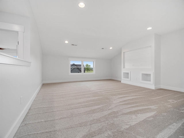 unfurnished living room featuring built in features, light carpet, and vaulted ceiling