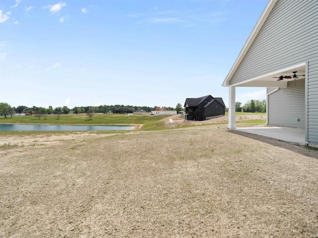 view of yard with a patio, a water view, and ceiling fan