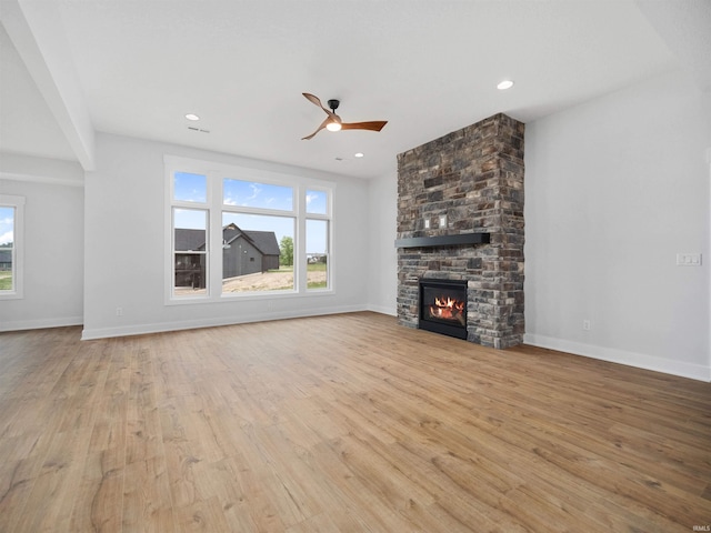 unfurnished living room featuring a stone fireplace, ceiling fan, and light hardwood / wood-style flooring