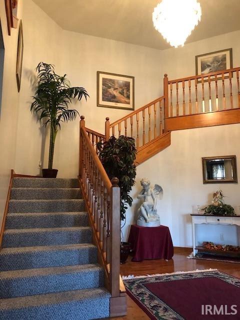 staircase with hardwood / wood-style flooring and a notable chandelier