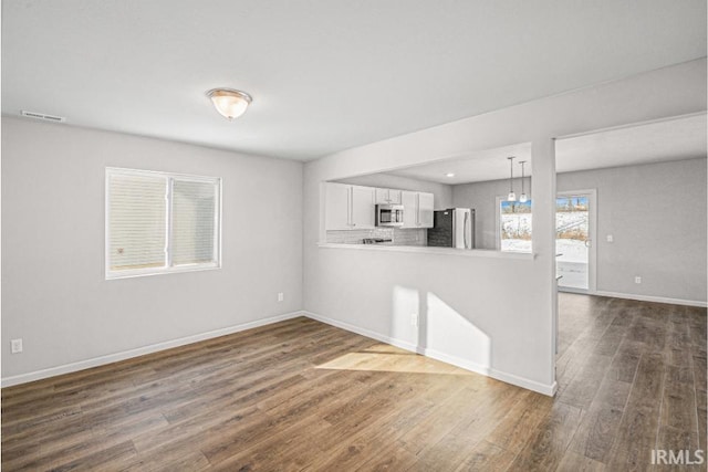 unfurnished room featuring dark wood-style floors, visible vents, and baseboards