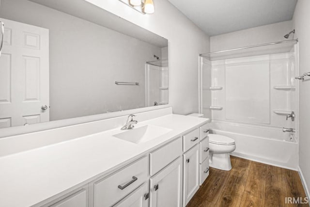 full bath with toilet,  shower combination, wood finished floors, and vanity