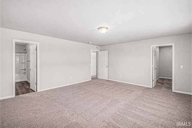 unfurnished bedroom with visible vents, baseboards, ensuite bathroom, a spacious closet, and carpet floors