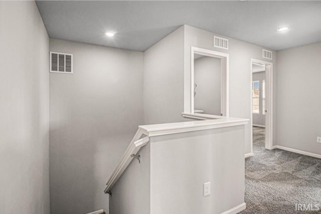 hallway featuring carpet, visible vents, and an upstairs landing