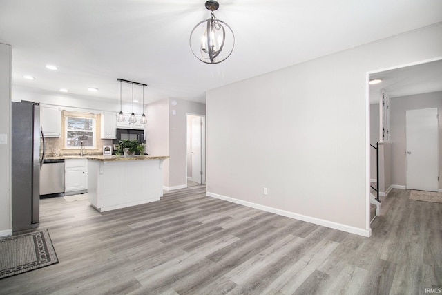 kitchen with light wood-type flooring, stainless steel appliances, pendant lighting, white cabinets, and a chandelier