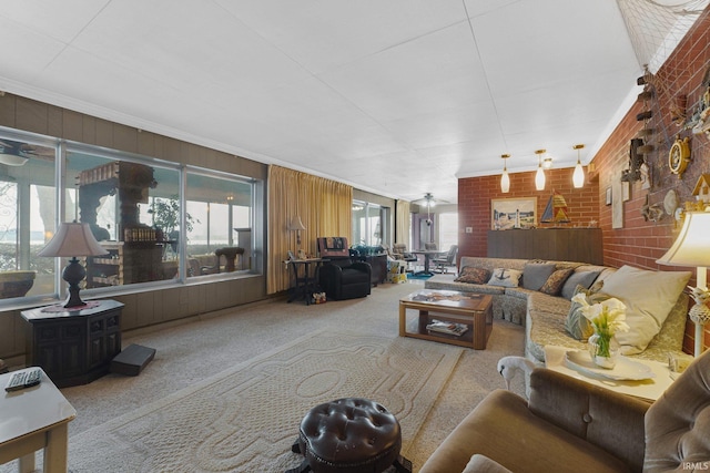 carpeted living room with ceiling fan, crown molding, and brick wall