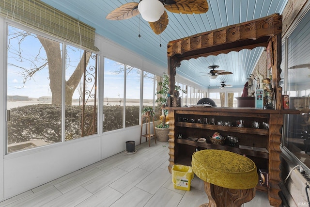 sunroom / solarium featuring ceiling fan and a water view