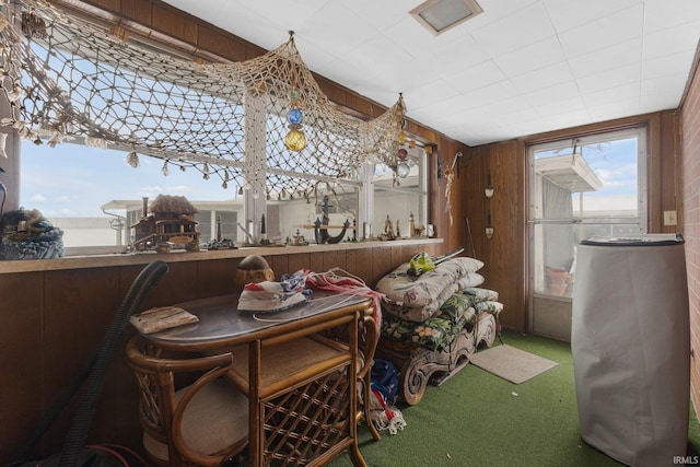 dining room with wooden walls, carpet, and a healthy amount of sunlight