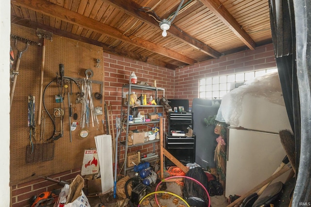 miscellaneous room featuring a workshop area, beamed ceiling, and brick wall