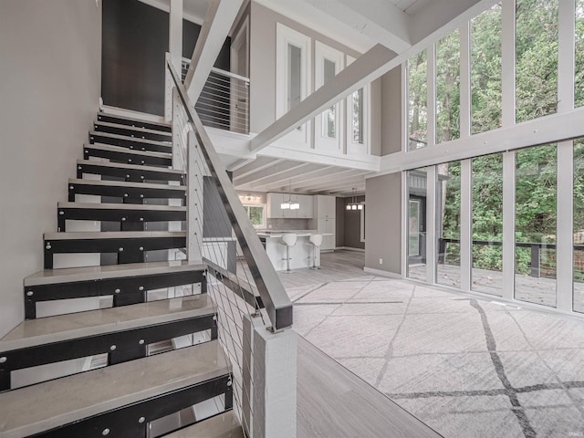 stairs with wood-type flooring, a high ceiling, and a notable chandelier