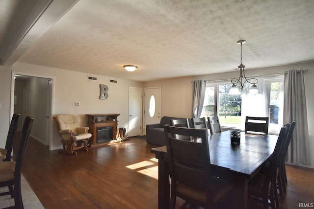 dining area featuring a textured ceiling, dark hardwood / wood-style flooring, and a notable chandelier