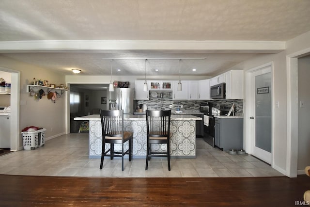 kitchen featuring a kitchen bar, tasteful backsplash, stainless steel appliances, decorative light fixtures, and a center island