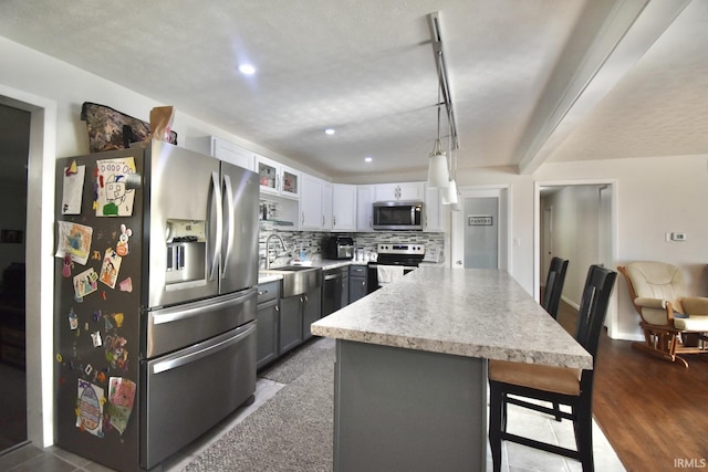 kitchen featuring backsplash, stainless steel appliances, sink, pendant lighting, and gray cabinets