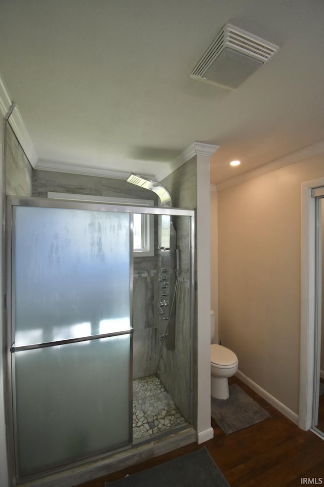 bathroom with hardwood / wood-style flooring, toilet, a shower with shower door, and crown molding